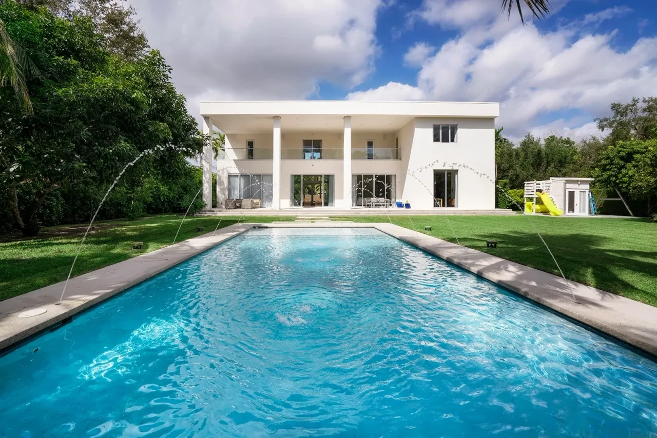 Modern home pool with fountain jets and manicured lawn