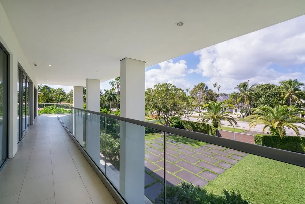 Second floor balcony with glass railing and garden views